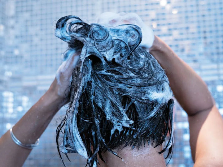 person lathering shampoo into hair