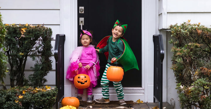 Kids in princess and dragon costumes holding jack o lantern buckets for trick or treating