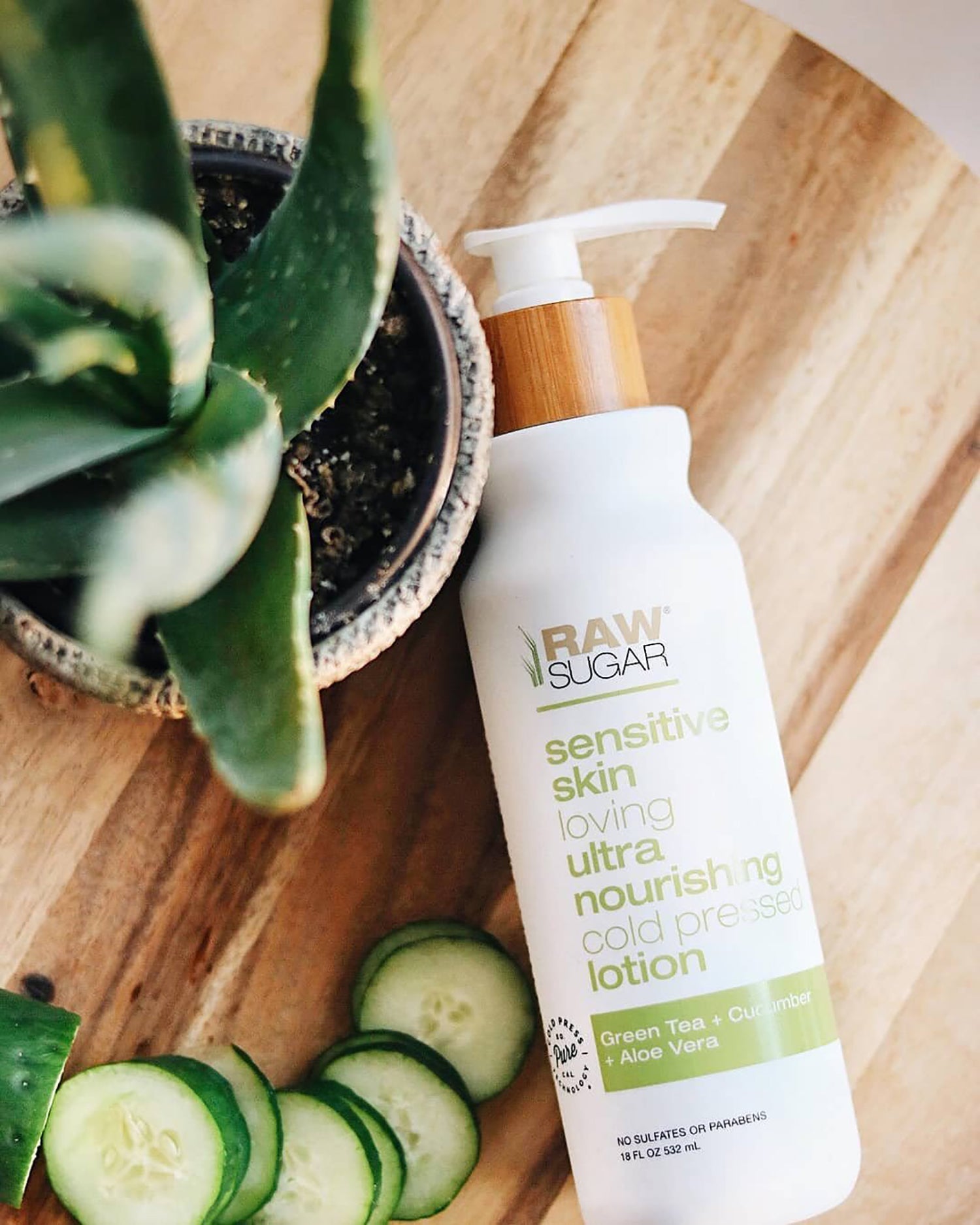 Raw Sugar Sensitive Skin Lotion next to aloe vera and cucumber