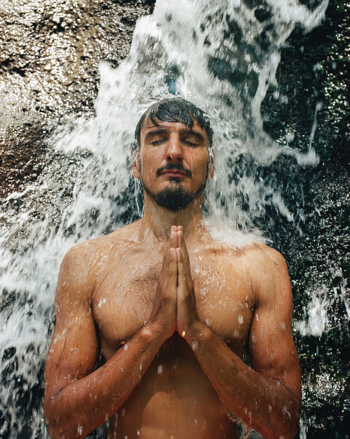 man with prayer hands standing under shower