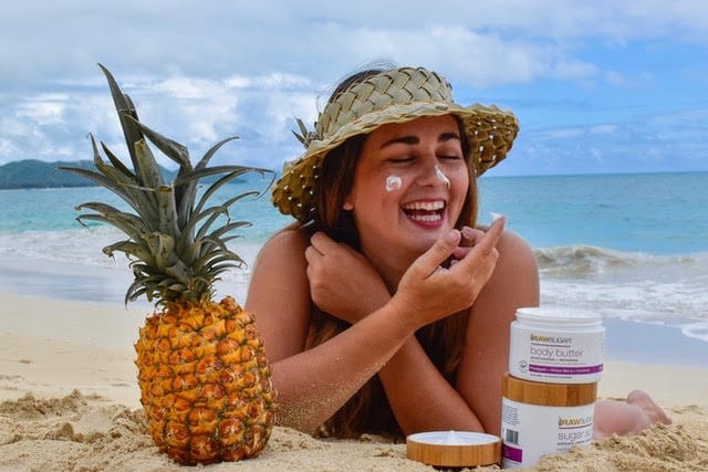 girl on beach moisturizing with body butter