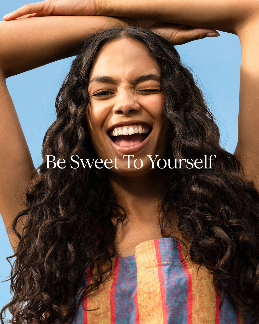 Woman with arms raised against a blue sky with 'Be Sweet To Yourself' text.