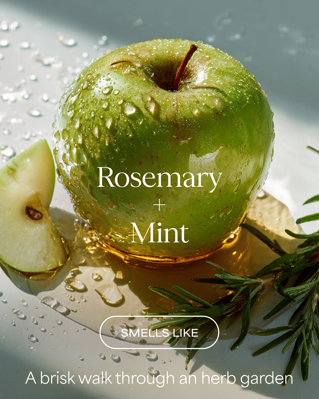 Green apple with water droplets, rosemary, and mint leaves on a reflective surface.