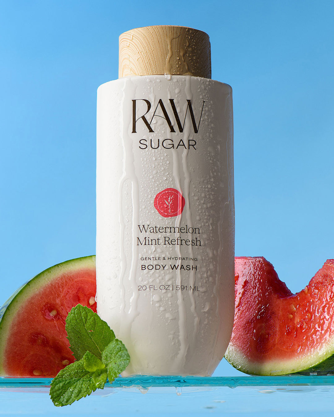 RAW Sugar Watermelon Mint Refresh body wash with watermelon slices and mint leaves on a blue background
