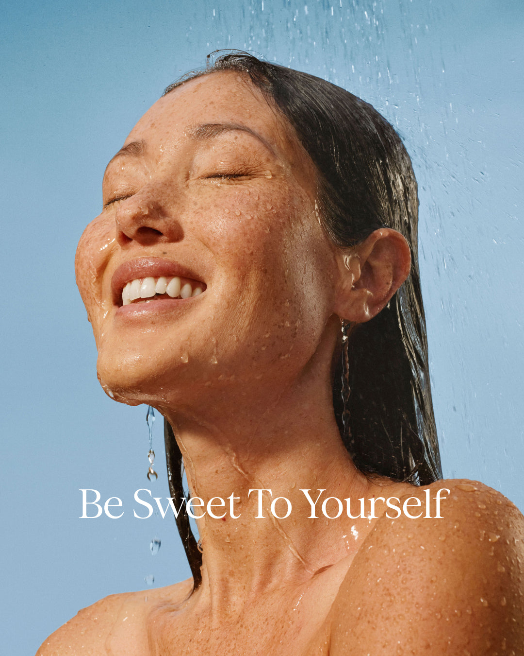Woman under a shower with 'Be Sweet To Yourself' text on a blue background