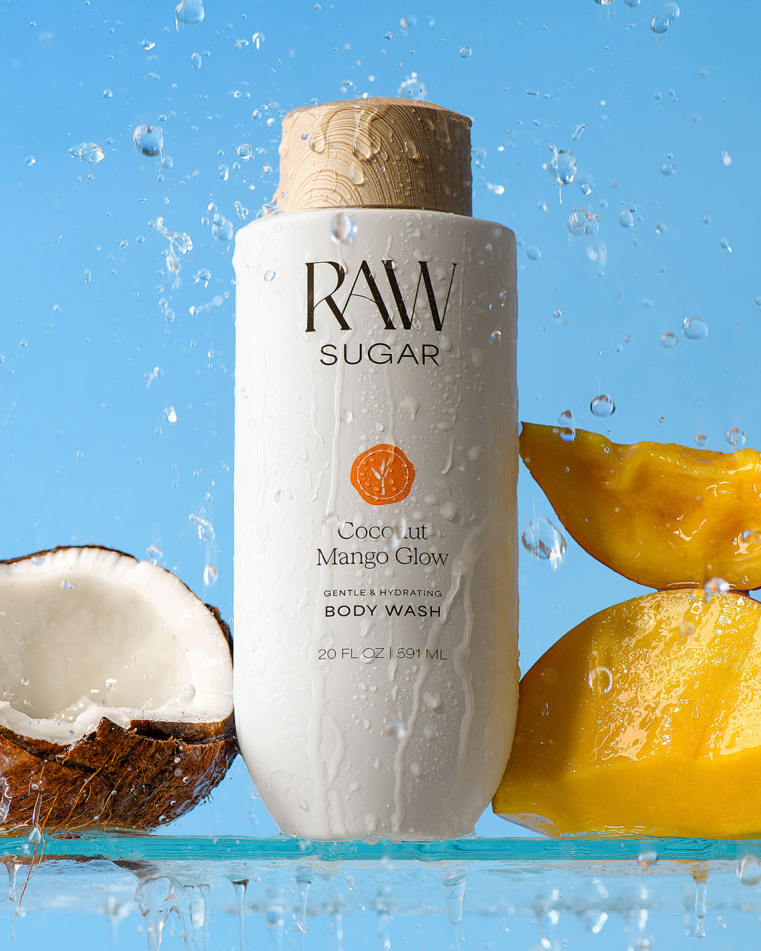 RAW Sugar coconut mango glow body wash bottle with coconuts and mangoes on a blue background, for Raw Sugar Body Wash designed to help gently cleanse and hydrate skin with clean ingredients.
