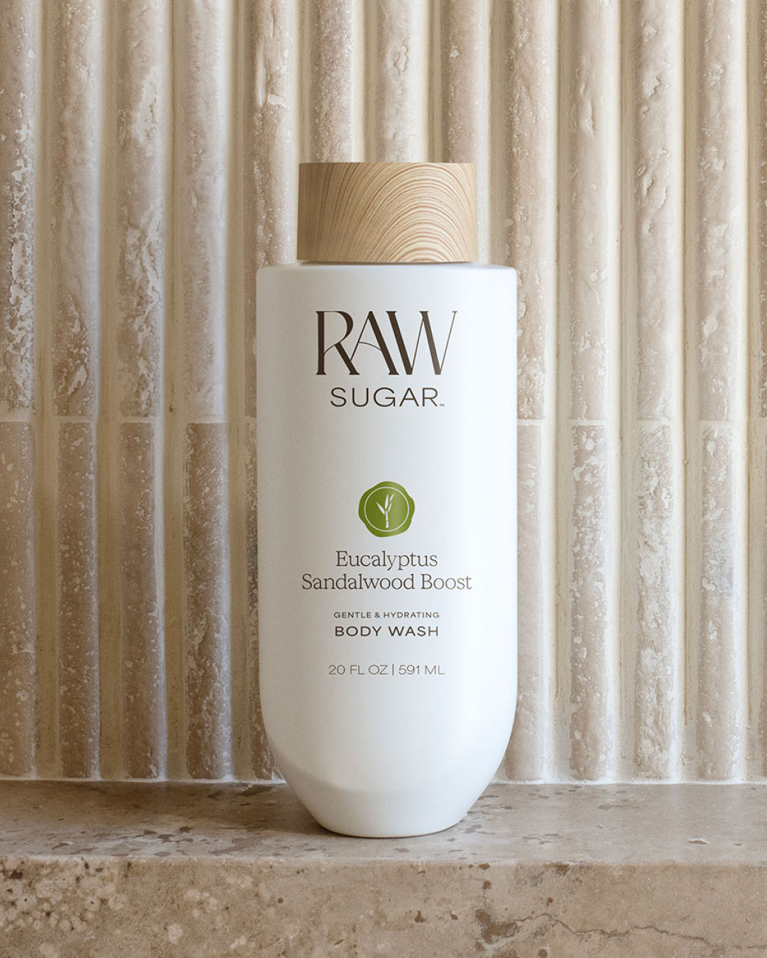 RAW Sugar body wash bottle with wooden cap on a textured stone background