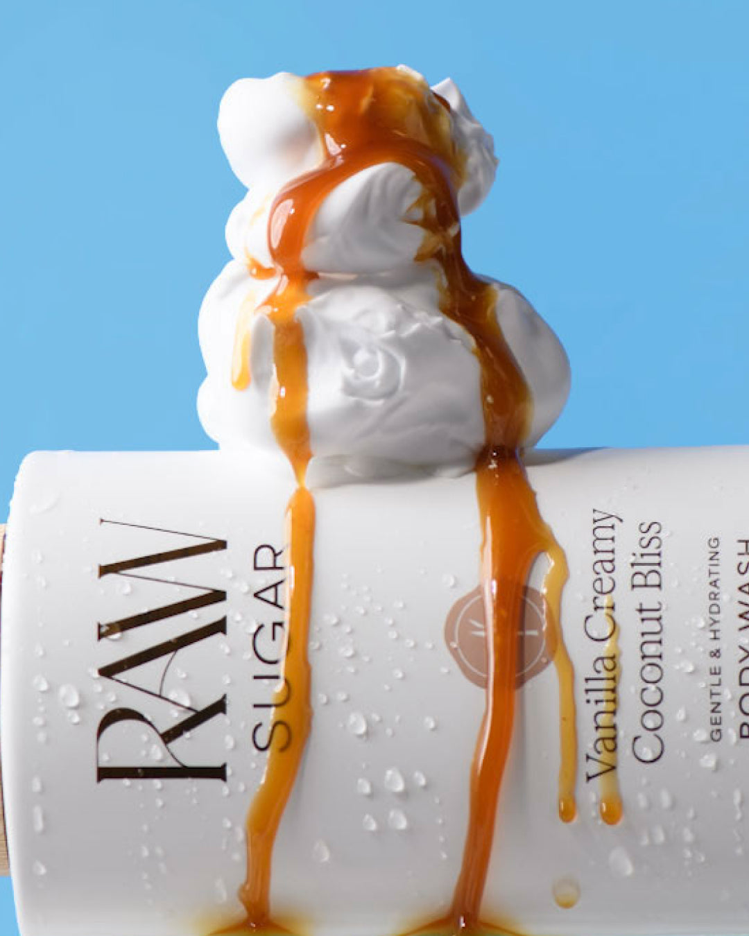 RAW Sugar Vanilla Creamy Coconut Bliss body wash with caramel drizzle on a blue background