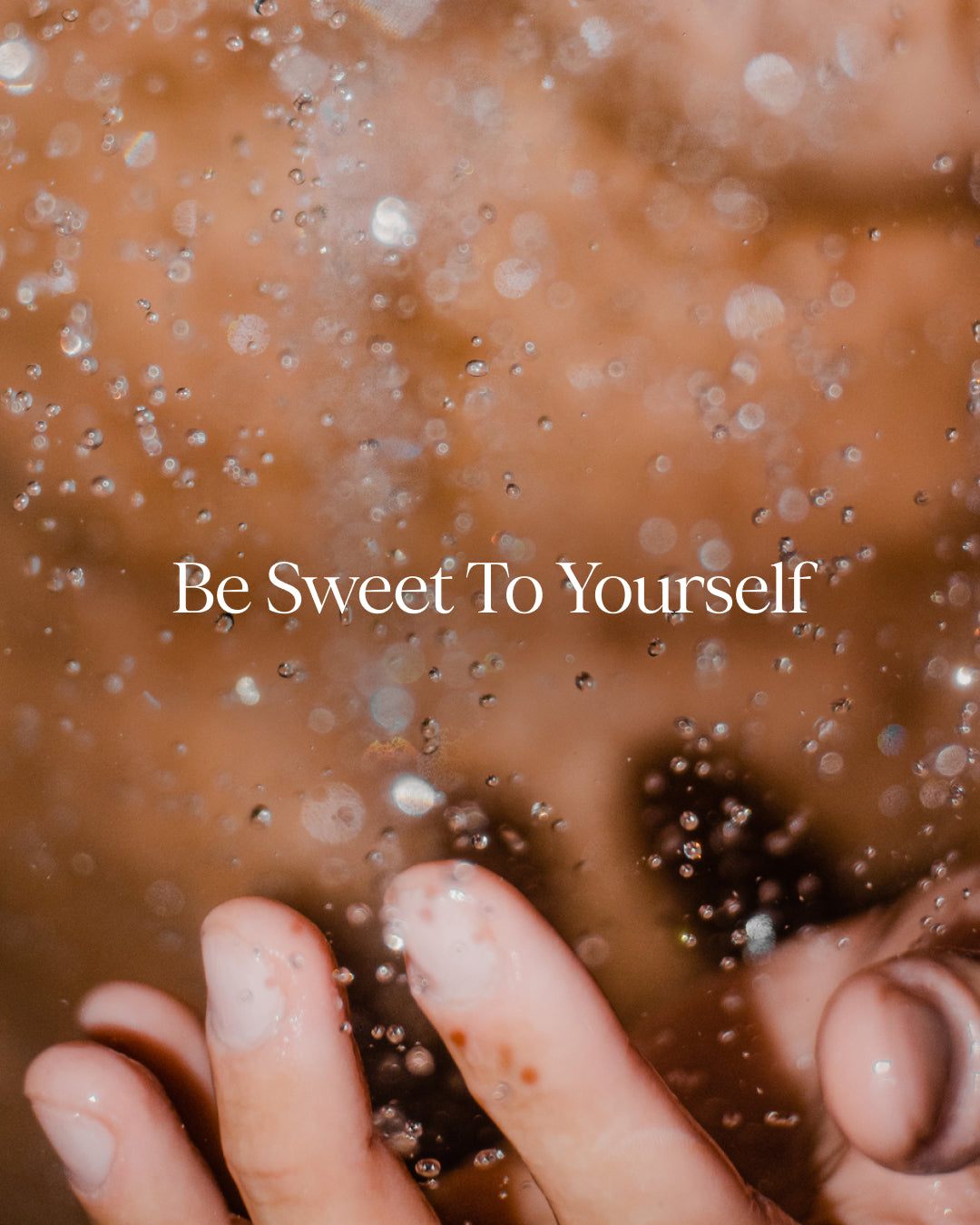 Text 'Be Sweet To Yourself' on a blurred background with hands near water droplets.