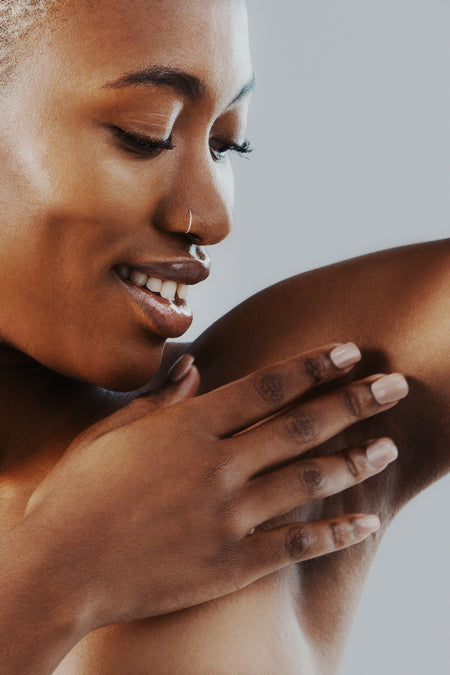 woman smiling and touching her armpit with hand