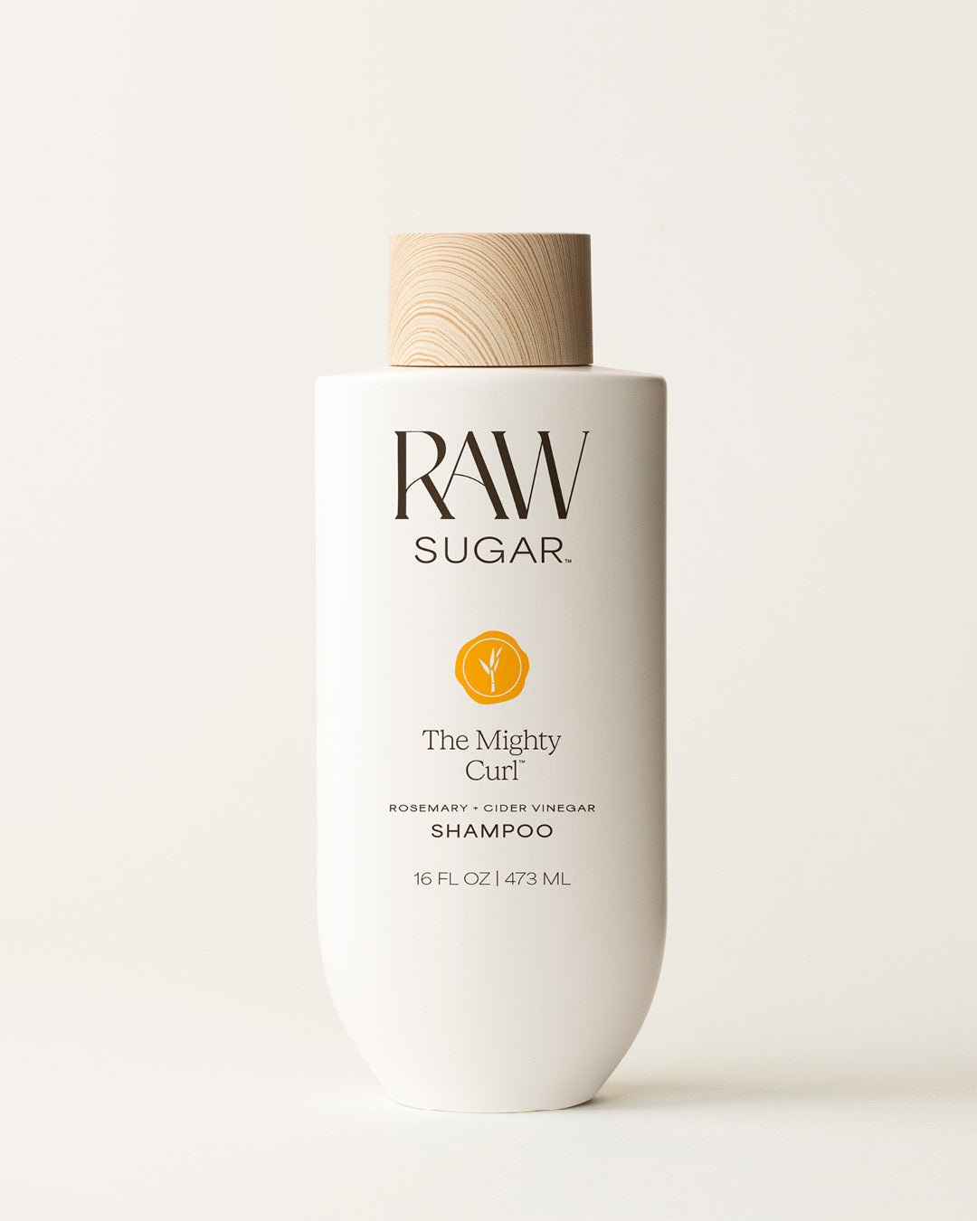 Bottle of Raw Sugar Mighty Curl Shampoo on a cream background, designed to help cleanse curly hair with clean ingredients.