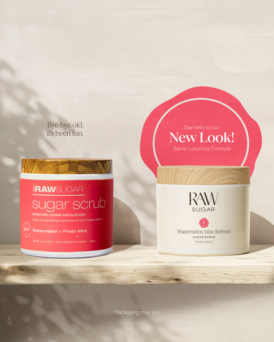 Two RAW SUGAR skincare products displayed on a light wooden shelf against a warm off-white background with soft leaf shadows. On the left is a red-labeled jar of sugar scrub with a gold lid, and on the right is a cream-colored jar with a wood lid under a pink promotional badge reading 'New Look!'.