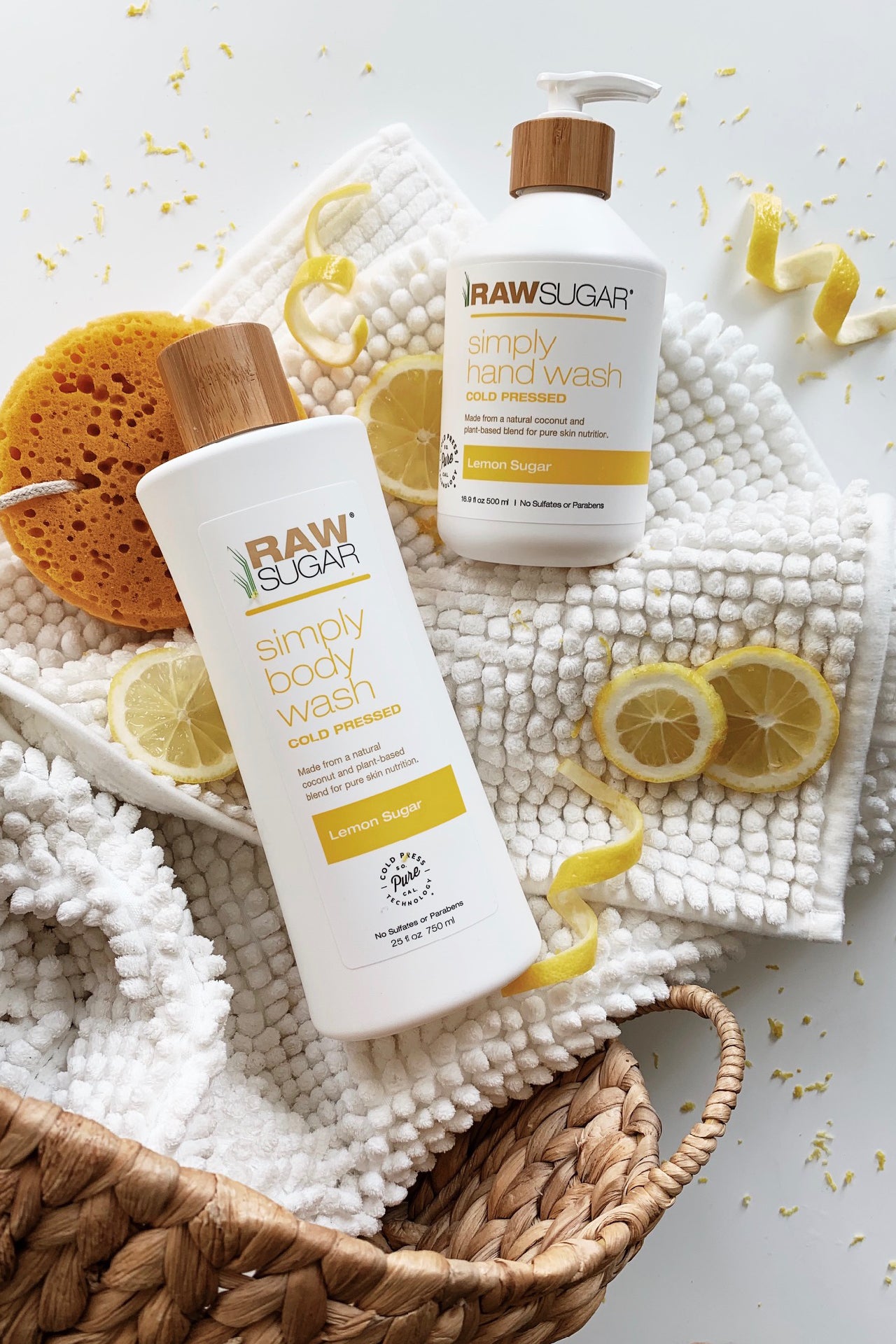 Raw Sugar Lemon Hand Wash and Body Wash laying on bath mat next to lemon slices