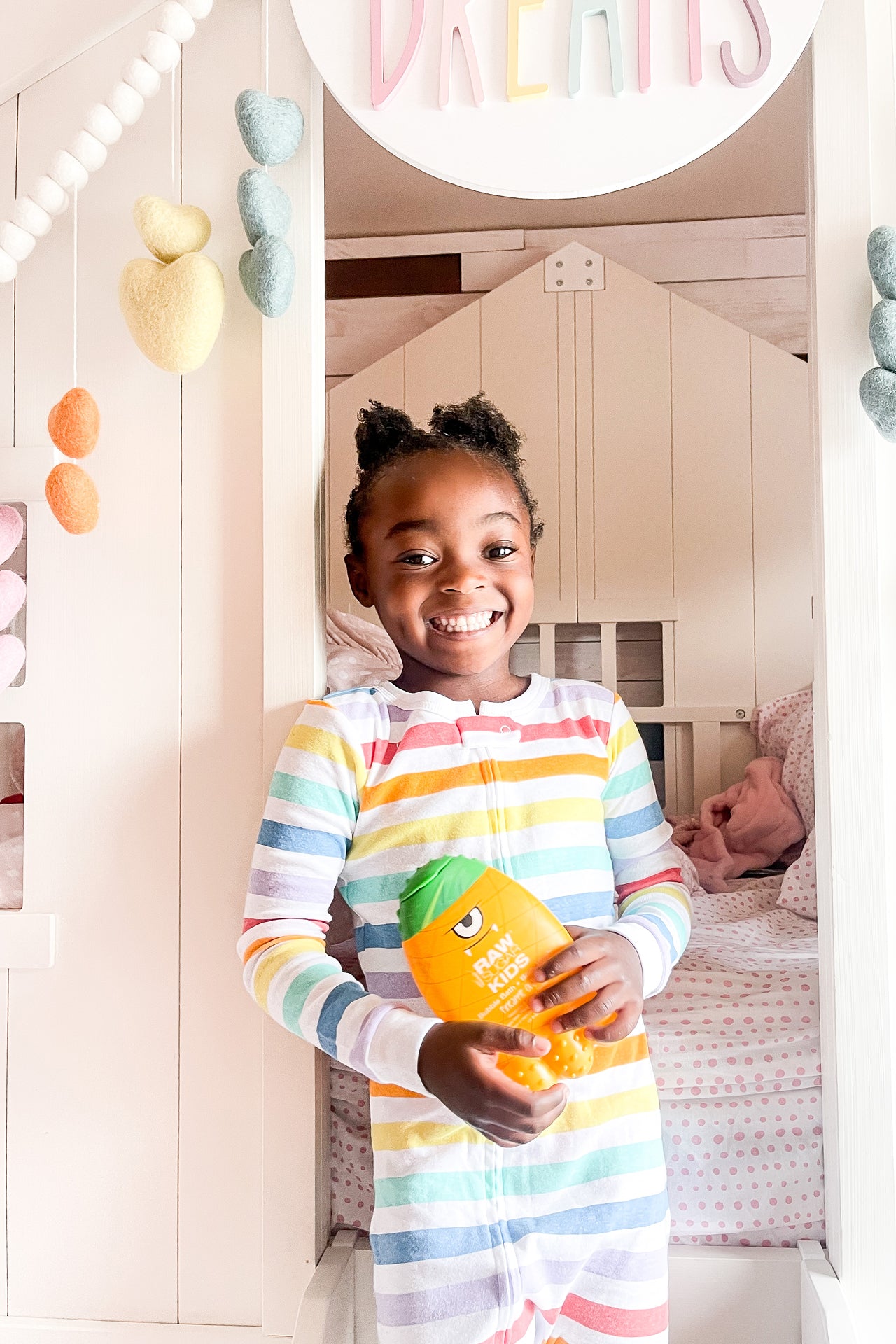 child in front of her bedroom holding 2-in-1 body wash and bubble bath