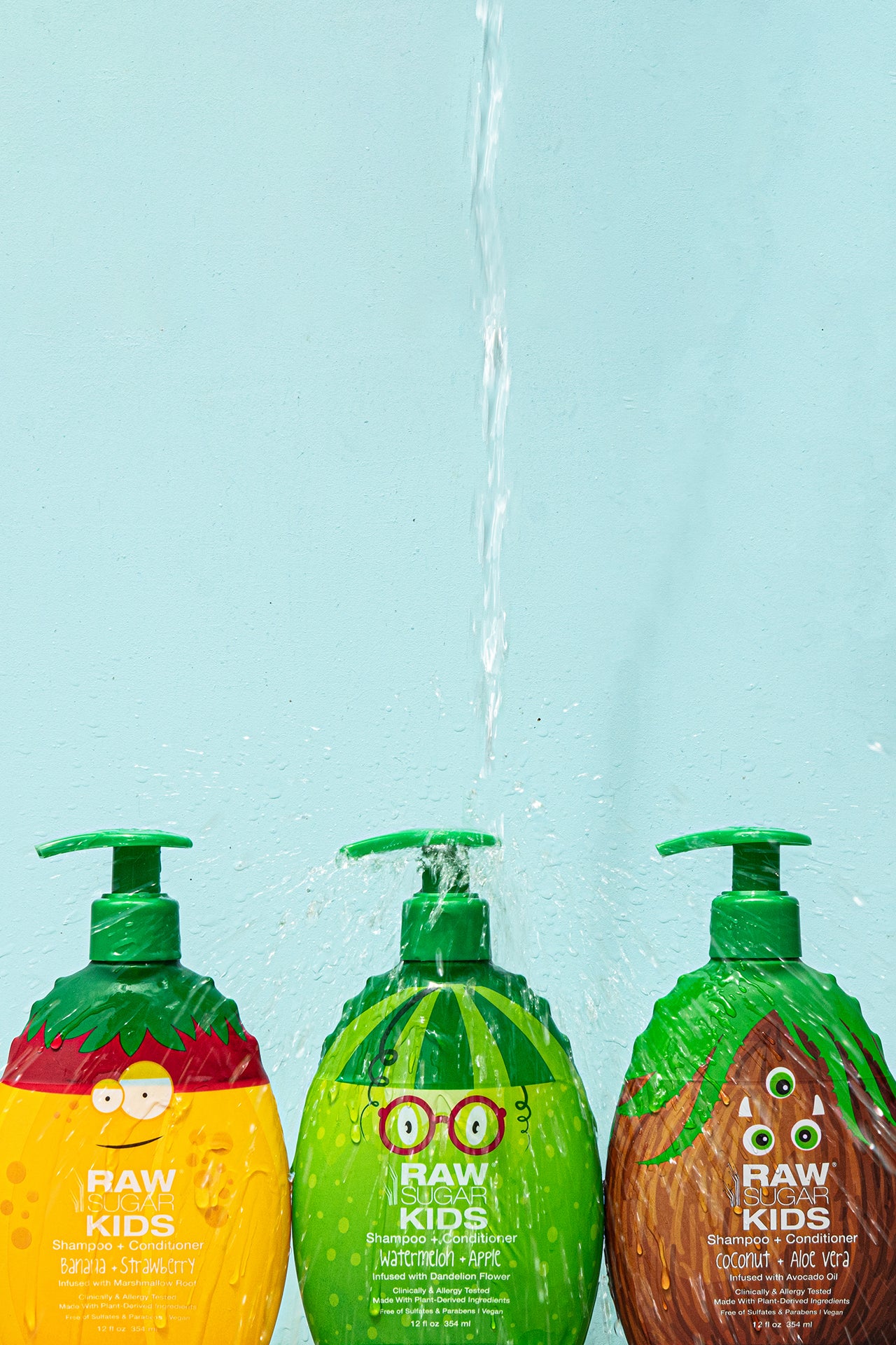 3 Raw Sugar Kids Shampoo Monster bottles with water pouring down on center bottle creating splashing effect over other bottles