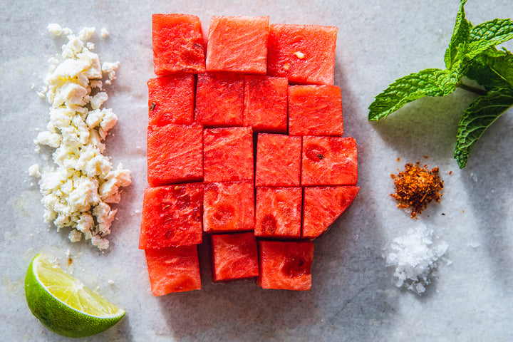 Cubed Watermelon next to spices cheese and limes