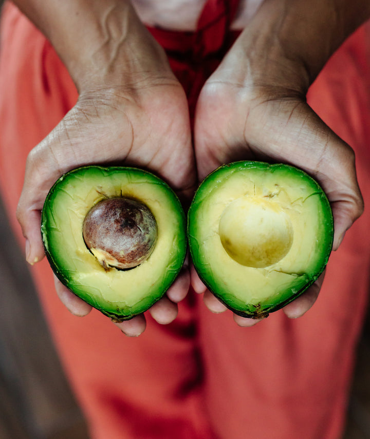 Avocado cut in half and held in hands