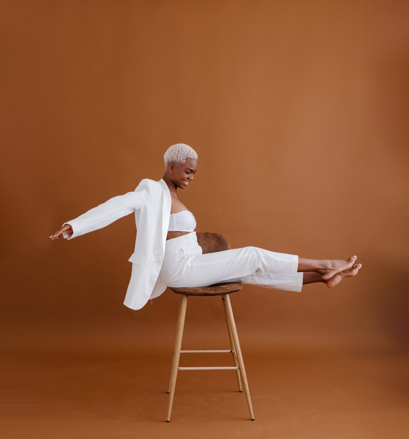 woman sitting on chair extending arms in white outfit