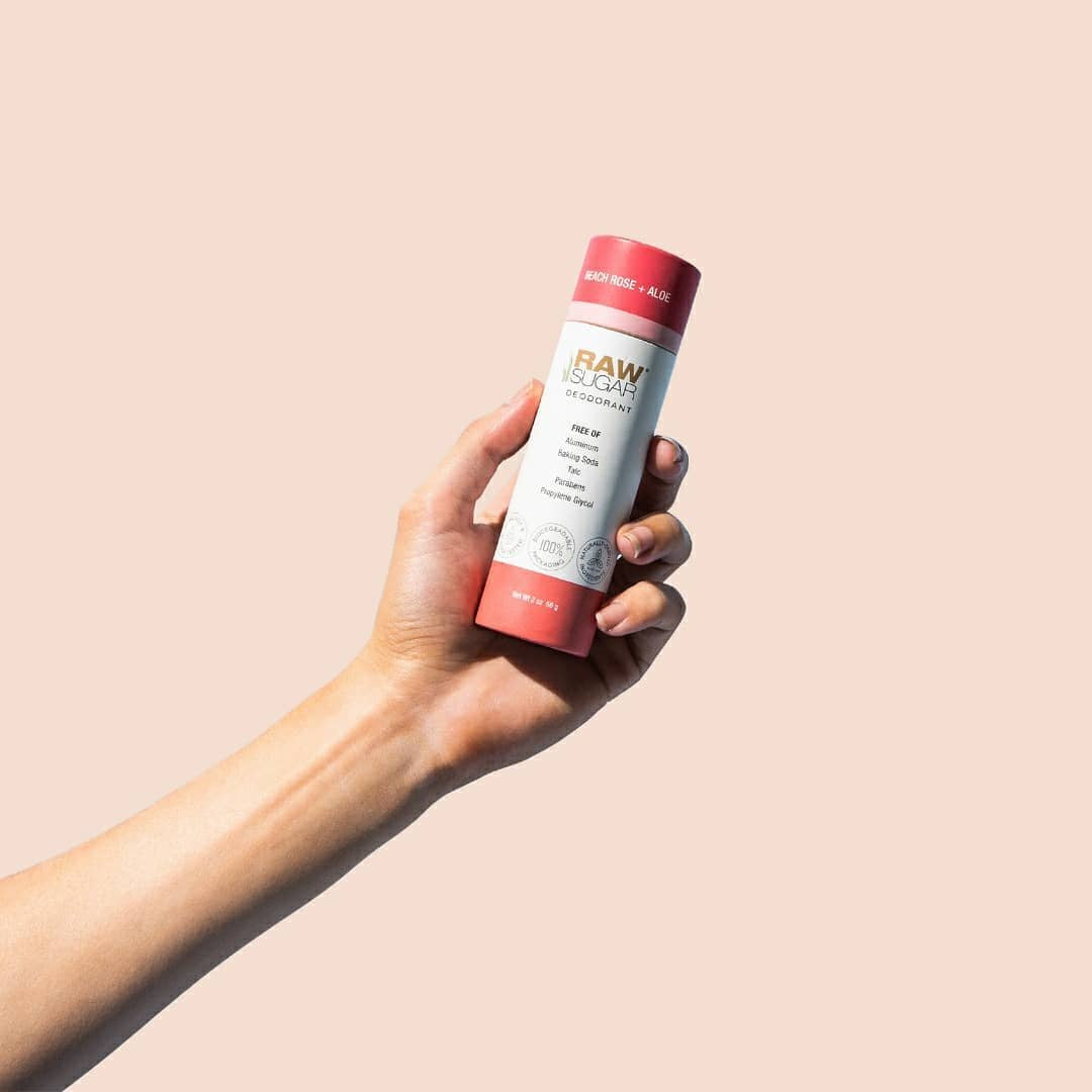 raw sugar beach rose + aloe deodorant held by hand