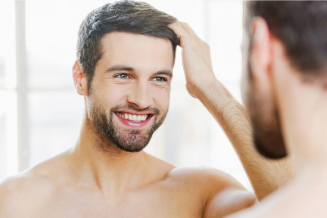 Man looking at himself in the mirror styling hair