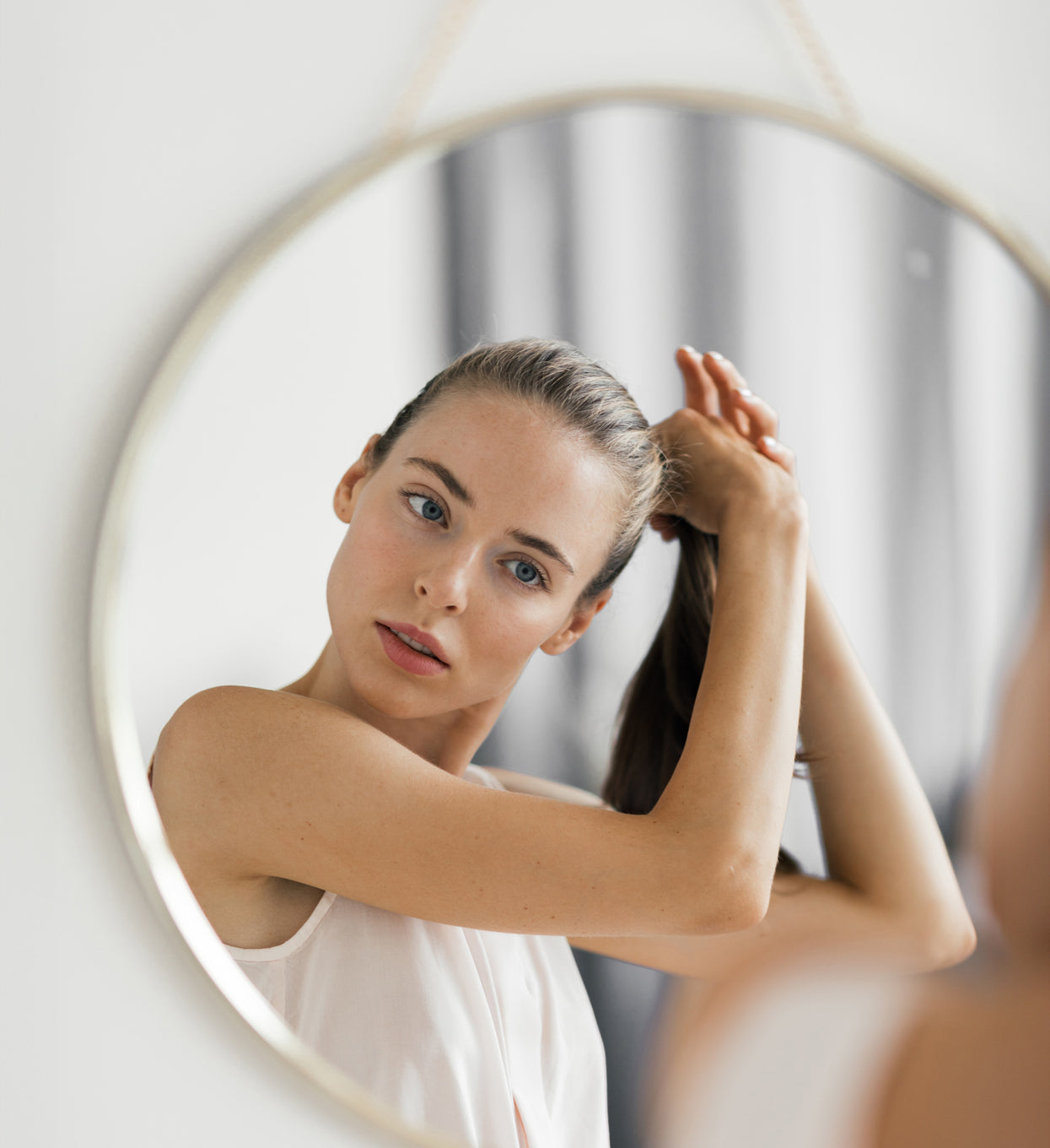 woman fixing hair looking in mirror