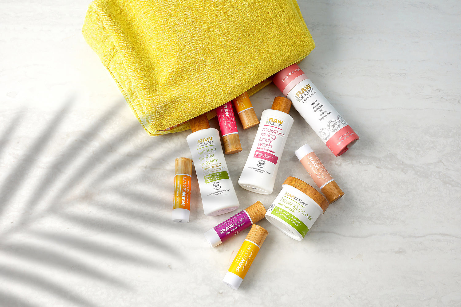 Raw Sugar travel sized products in a travel cosmetic bag and palm tree shadow