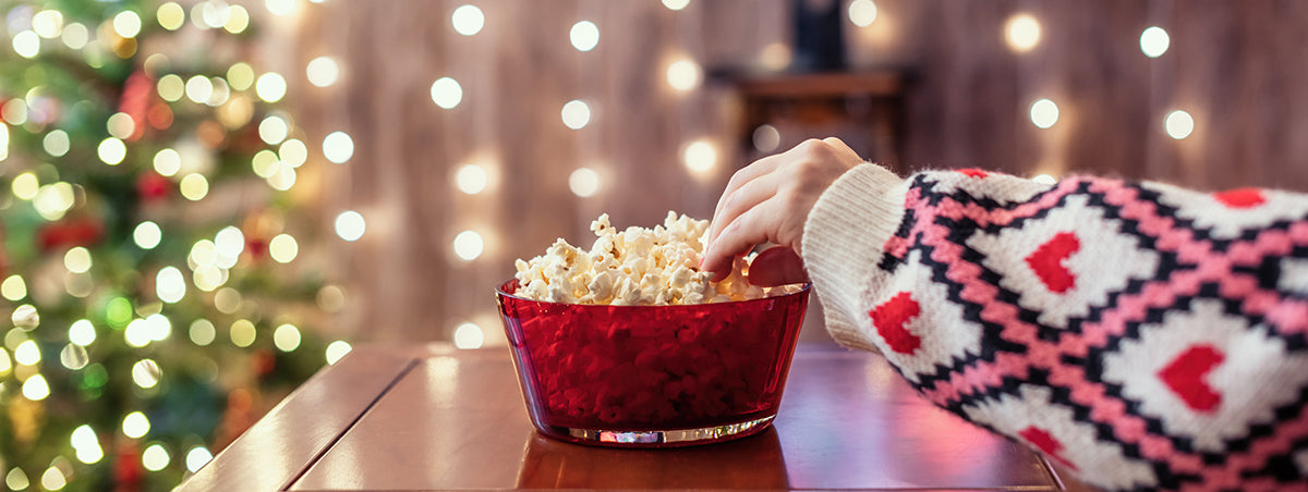 arm with christmas sweater reaching into pop corn bowl