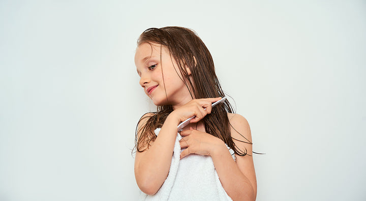 young girl in towel brushing hair with comb