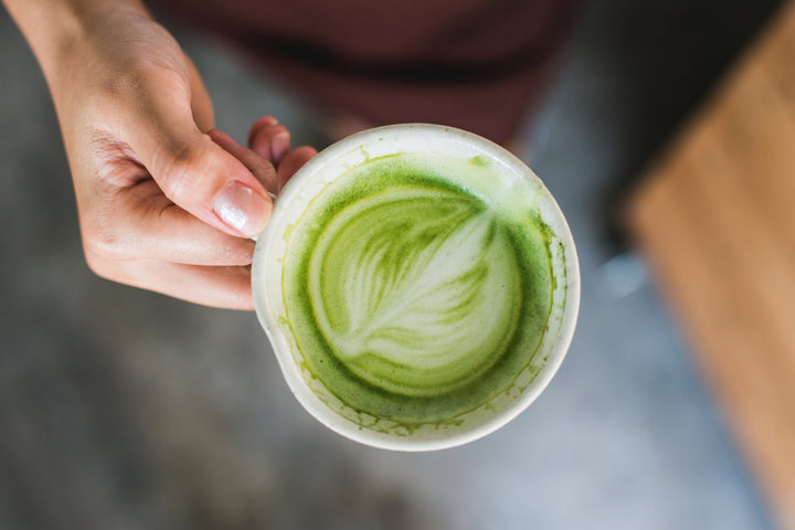 Green tea matcha latte being held with foam design