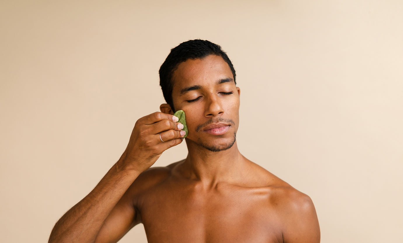 man using gua sha on face