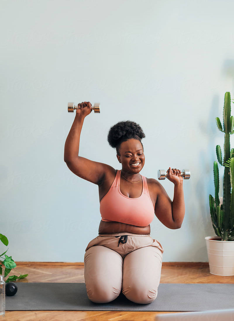woman working out on yoga mat with dumbbells at home