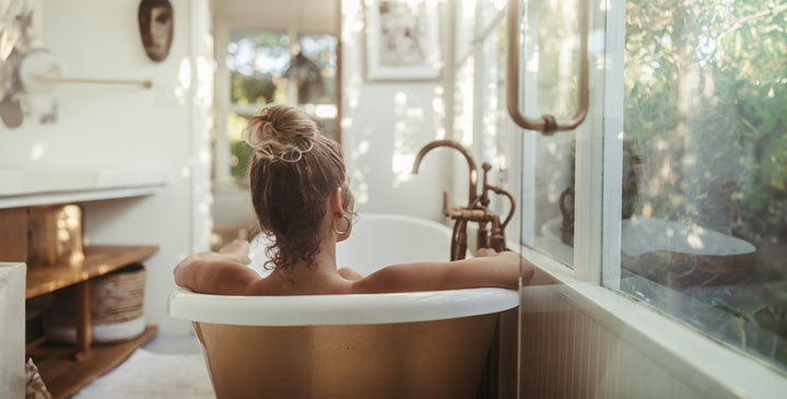 woman in bath tub staring out window