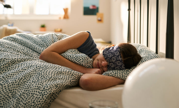 person sleeping in bed with eye mask