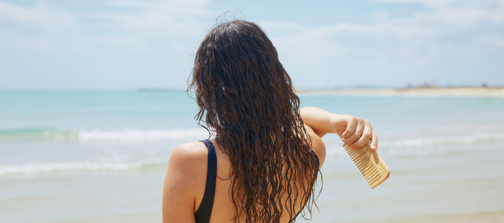 Woman combing wet hair on beach
