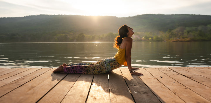 Girl doing yoga on dock by lake