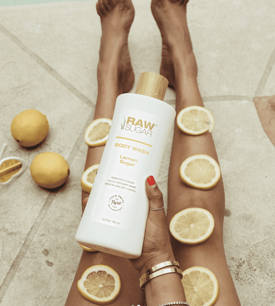 Woman holding Lemon Sugar Body Wash with lemon slices on her legs