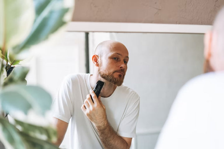 bald man trimming his beard