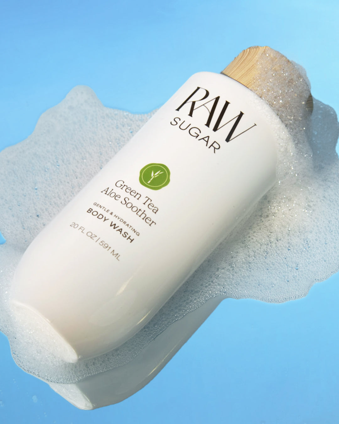 RAW Sugar Green Tea Aloe Soother body wash bottle with a wooden cap on a blue background for Raw Sugar Body Wash designed to help gently cleanse and hydrate skin with clean ingredients.