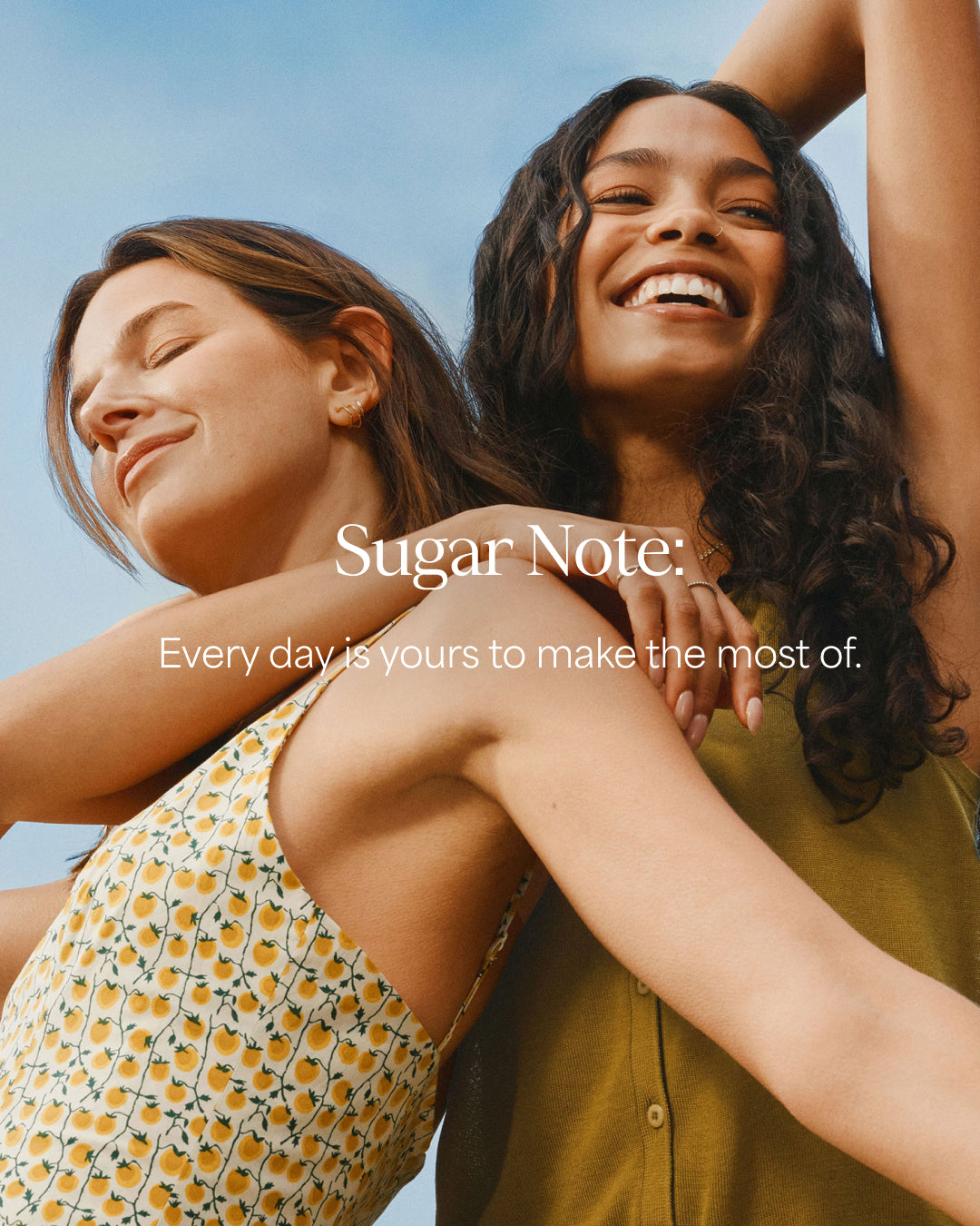 Two women embracing with a clear blue sky in the background, featuring the 'Sugar Note' brand.