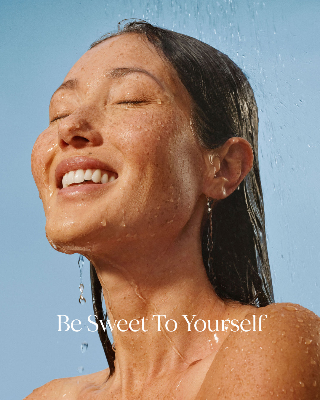 Woman under a shower with 'Be Sweet To Yourself' text on a blue background