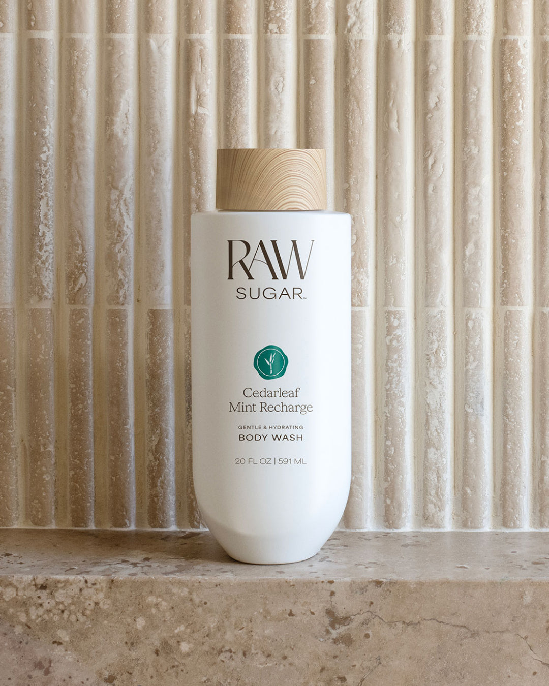 RAW Sugar body wash bottle on a stone surface with a textured wall background