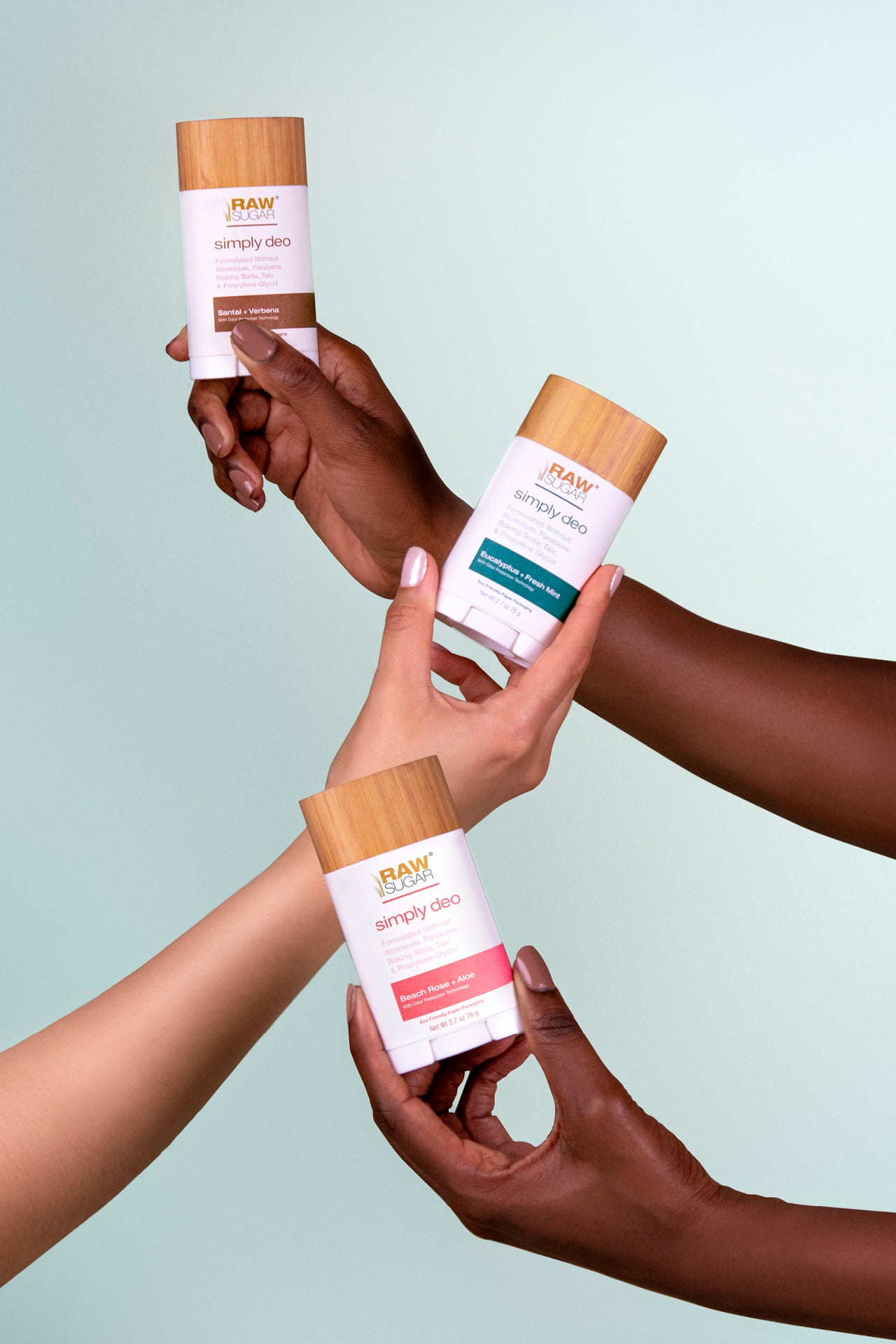 three hands holding aluminum free deodorant