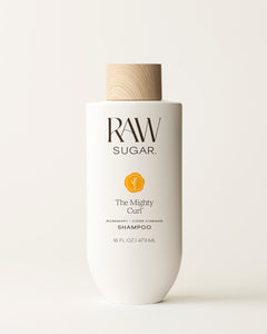 Bottle of Raw Sugar Mighty Curl Shampoo on a cream background, designed to help cleanse curly hair with clean ingredients.