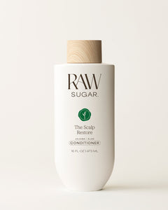 Bottle of Raw Sugar Scalp Restore Conditioner on a cream background, designed to help soothe scalp and hair with clean ingredients.