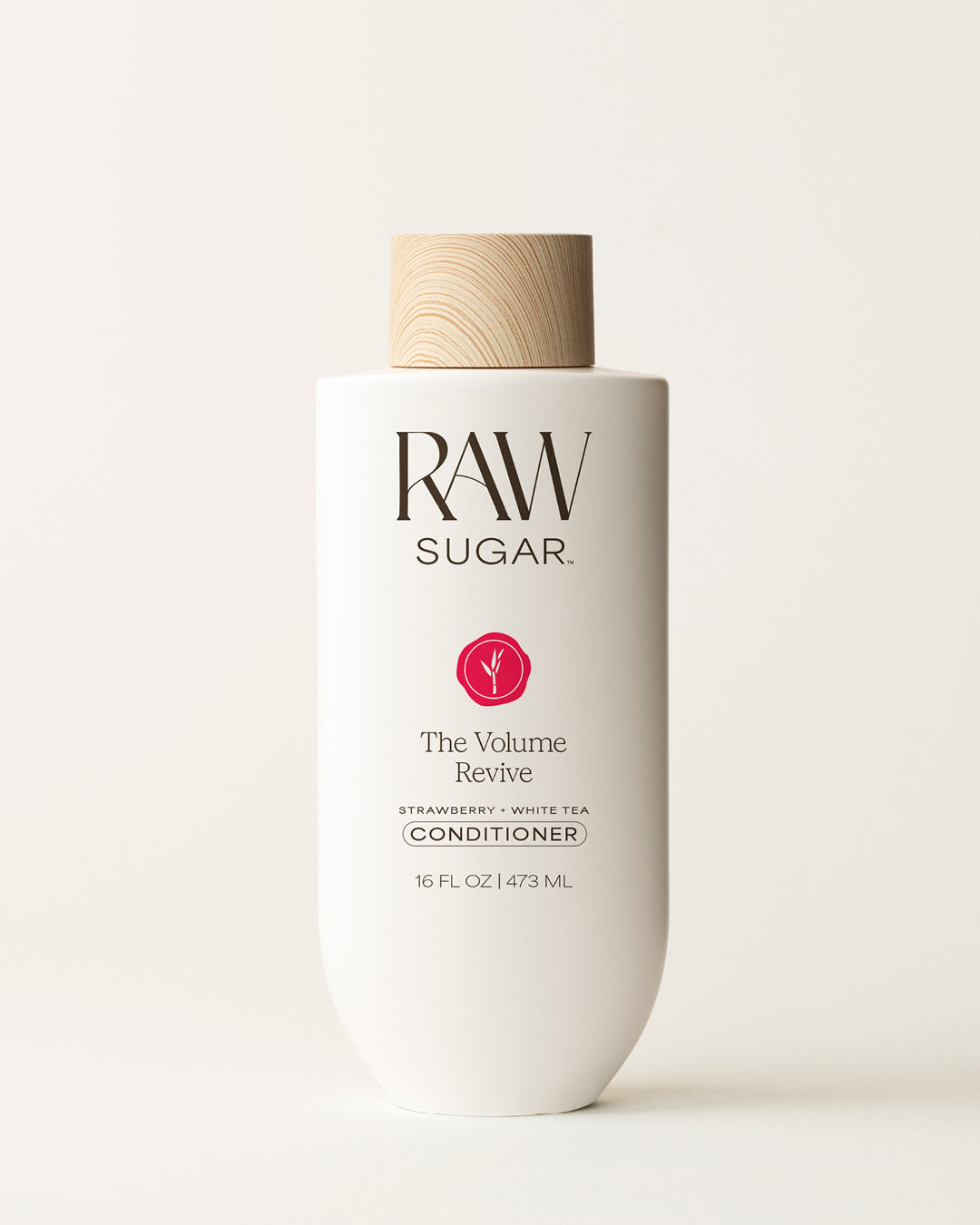 Bottle of Raw Sugar Volume Revive Conditioner on a cream background, designed to moisturize hair with clean ingredients.