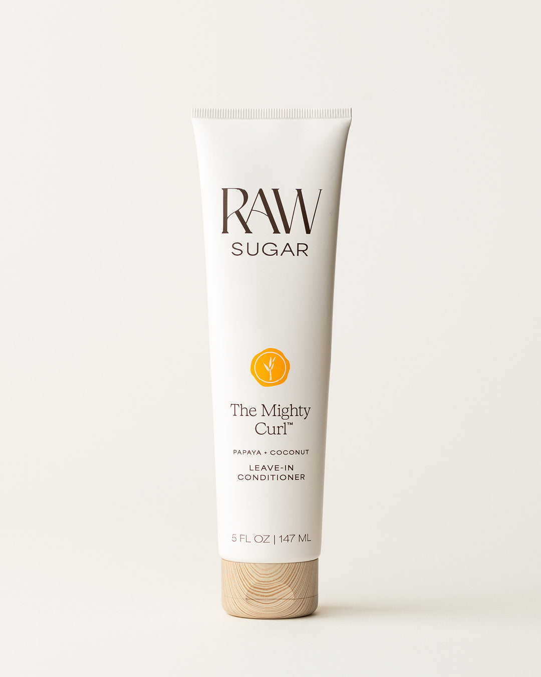 Bottle of Raw Sugar Leave-In Conditioner on a cream background, designed to help nourish curly hair with clean ingredients.