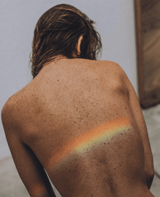 Image of Woman's Back with Rainbow Shining On It
