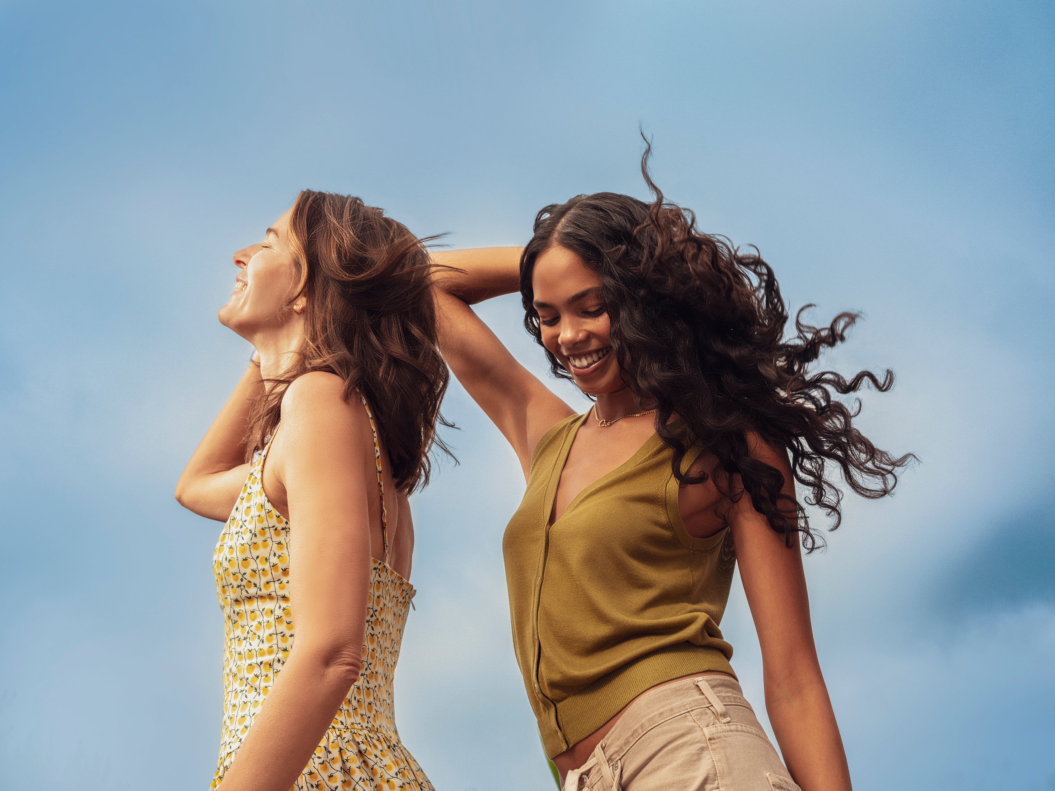 two women moving around outside against blue background
