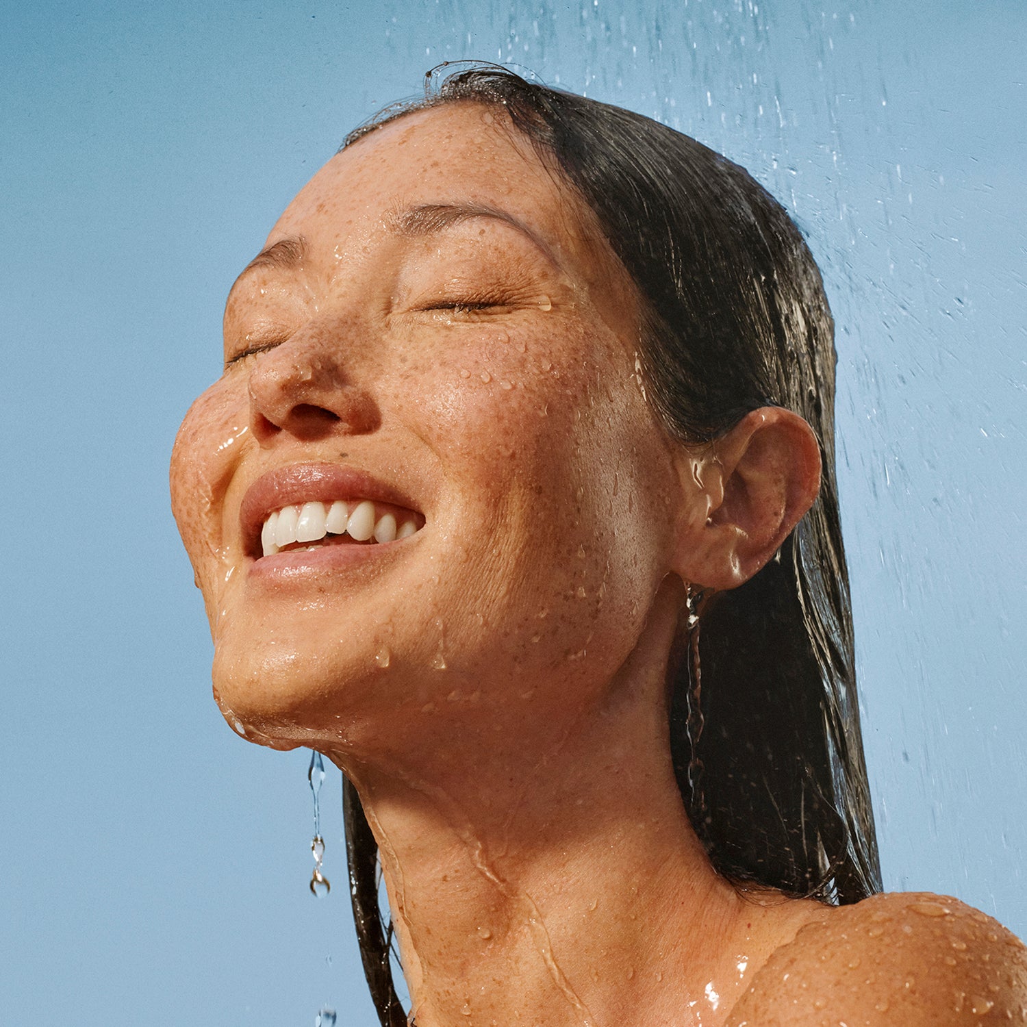woman showering and smiling using Raw Sugar clean personal care