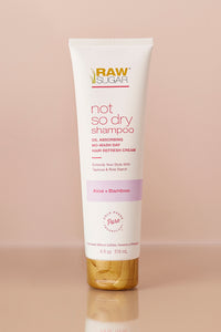 vegan dry shampoo bottle in front of pink background